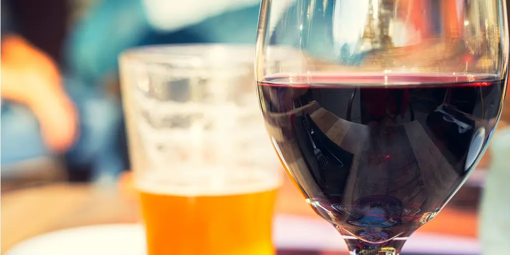 Red,Wine,And,Beer,Glass,On,Wooden,Table,With,Blurry